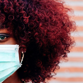 woman with curly hair wearing a mask