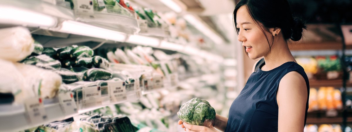 A woman in the aisle of the supermarket checking out the vegetables