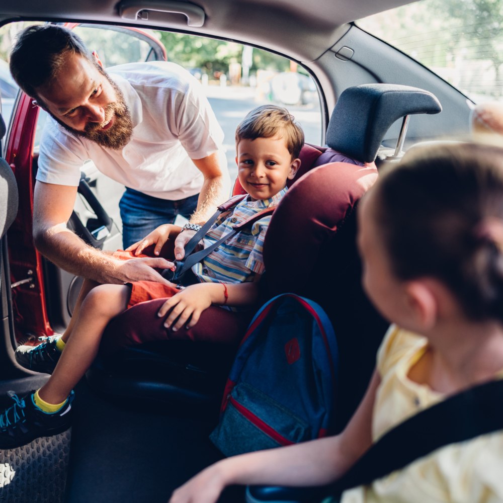 father preparing kids for travel in a car