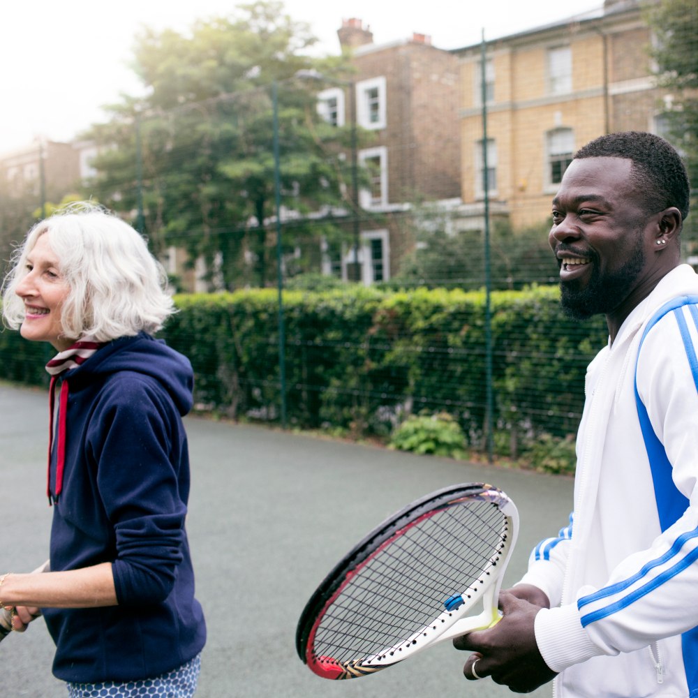 older woman and black man playing tennis
