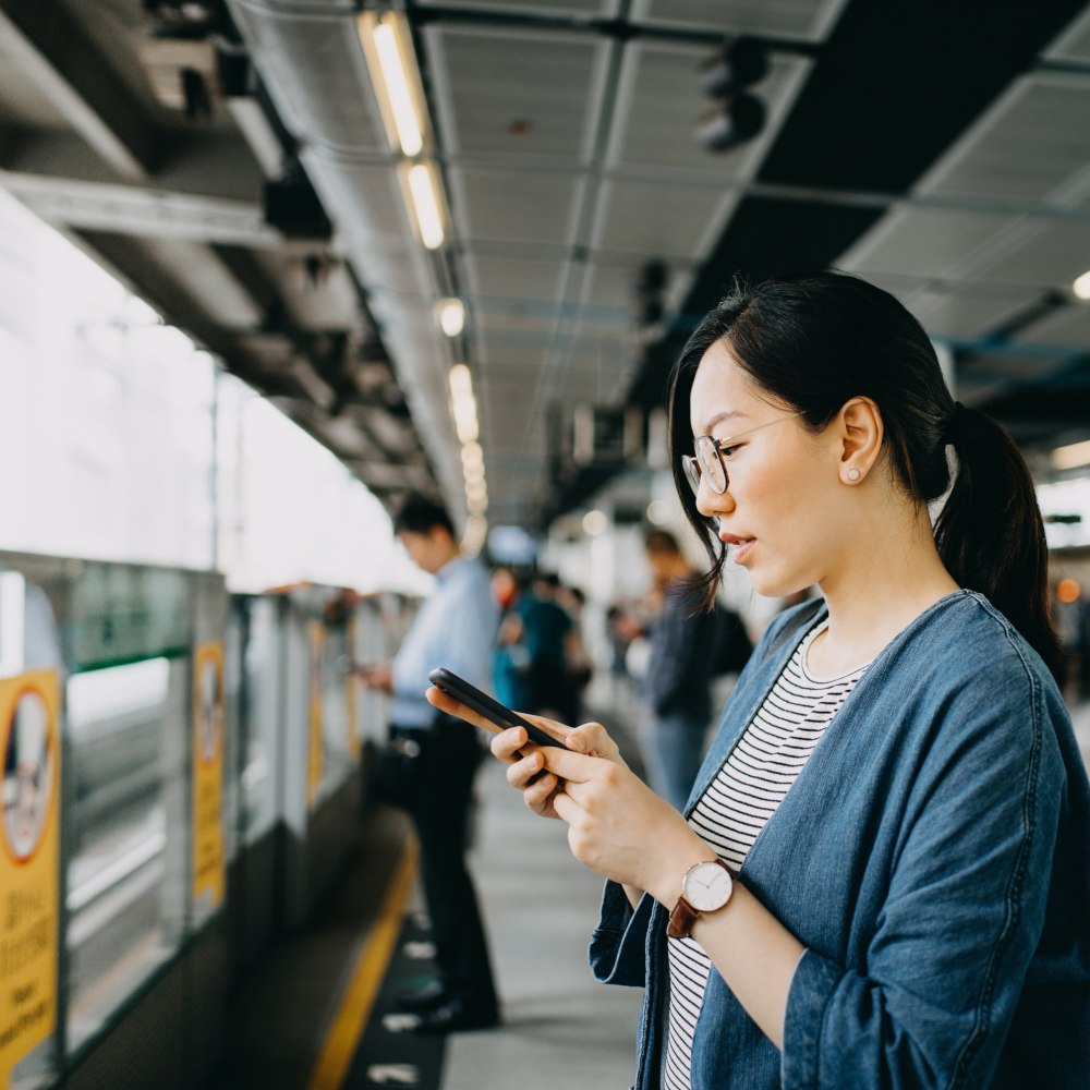 asian woman on a train station using her phone