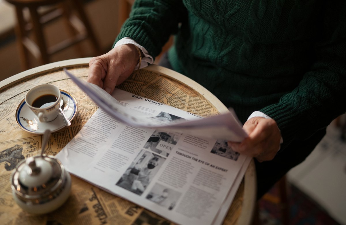 Image depicting a person reading a newspaper