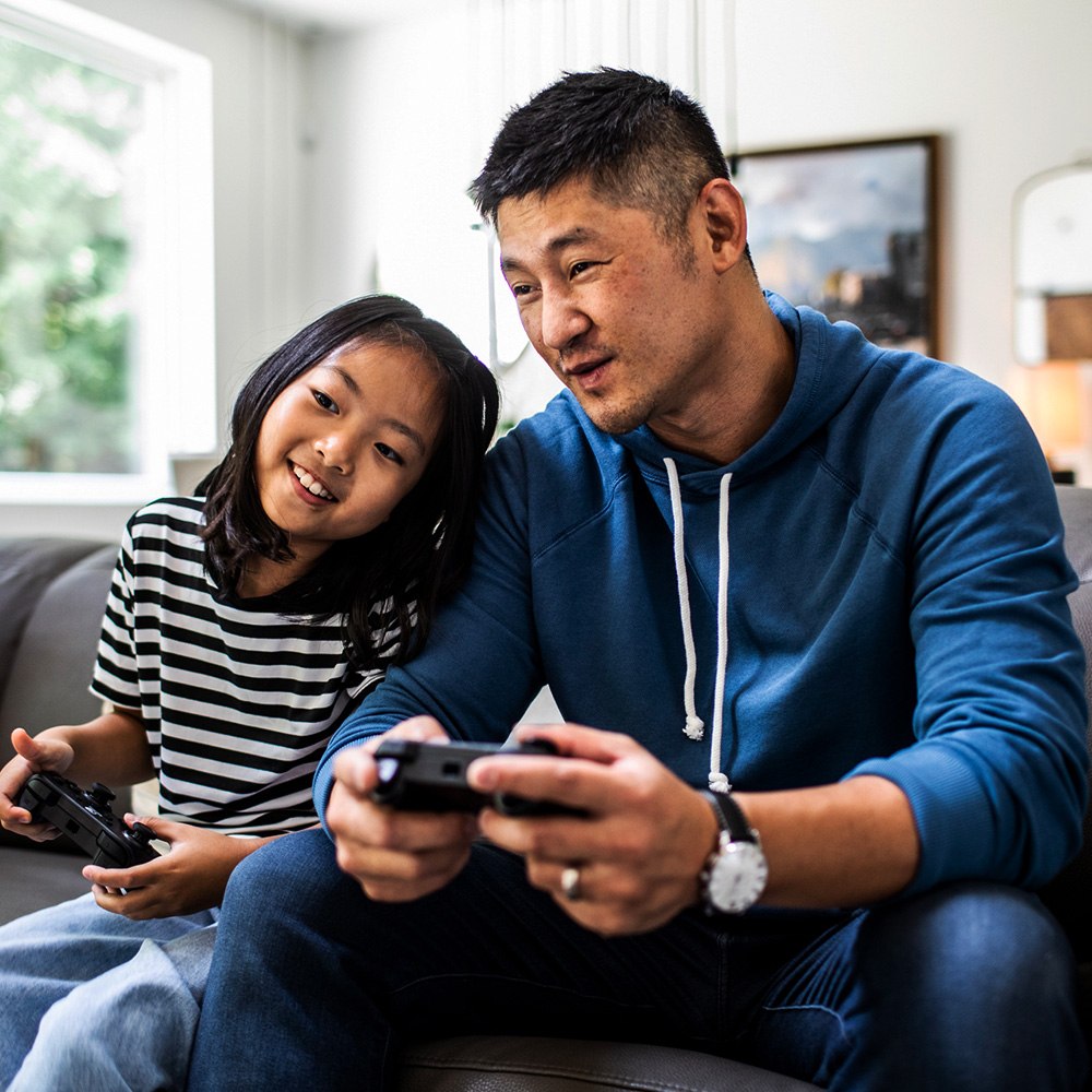 A man playing video game with daughter